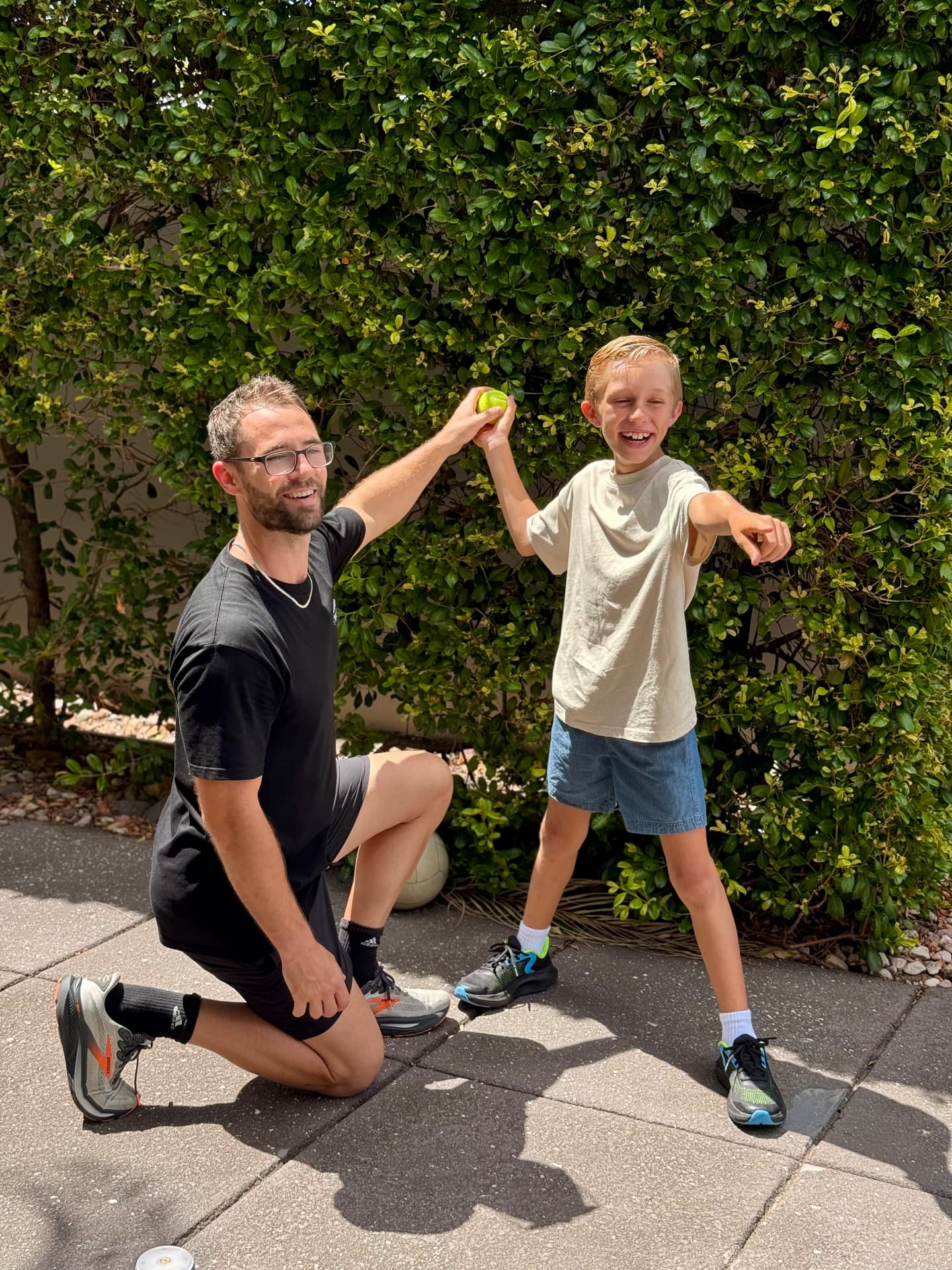 Isaac McCrimmon celebrating a successful ball throw with a child outdoors