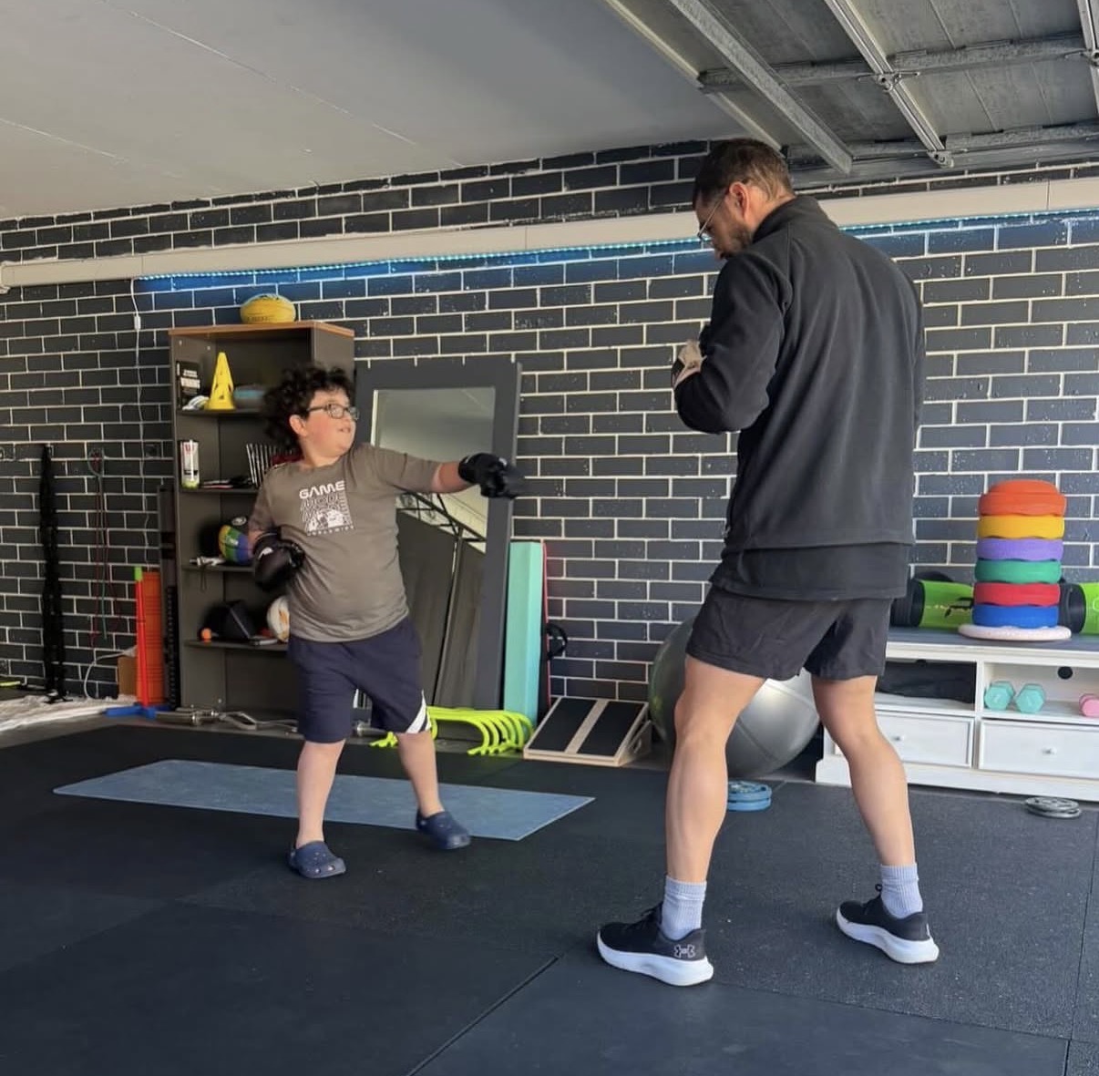 Isaac McCrimmon coaching a child through boxing drills in a gym space