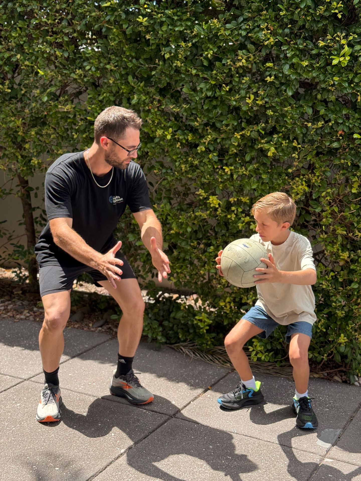 Isaac McCrimmon coaching a child to catch a ball during an outdoor session