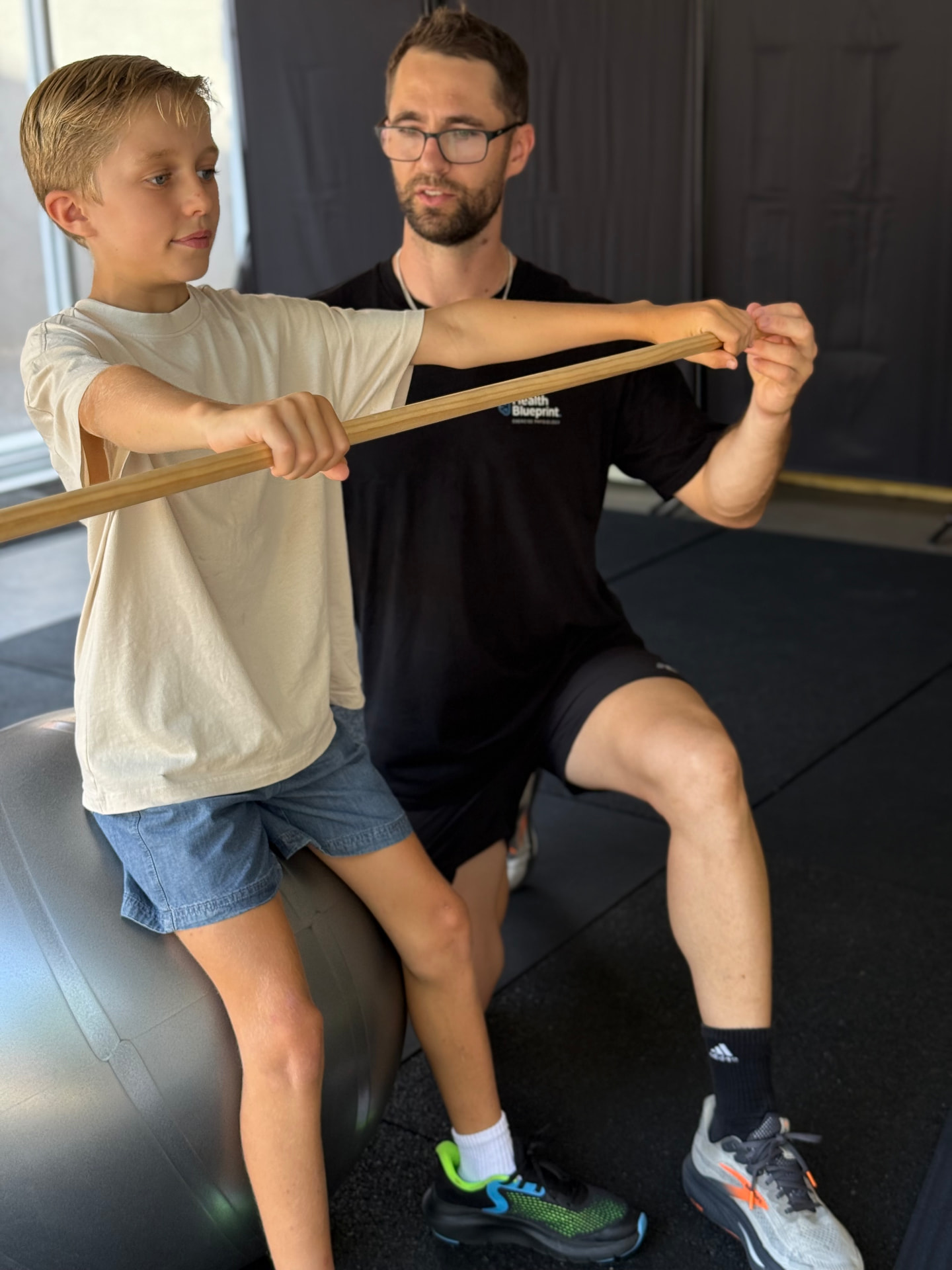 Isaac McCrimmon coaching a child through resistance band exercises in the clinic